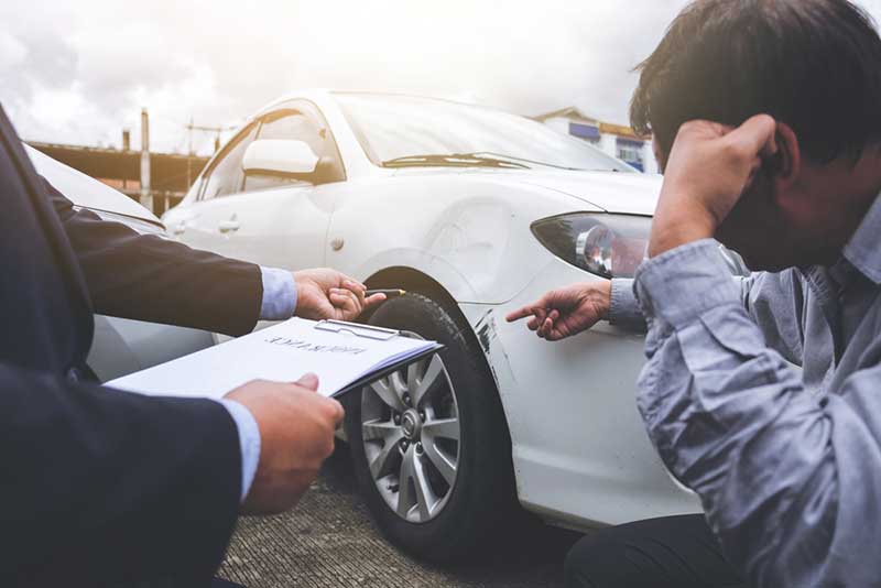 examining damaged car man examining damage in a car